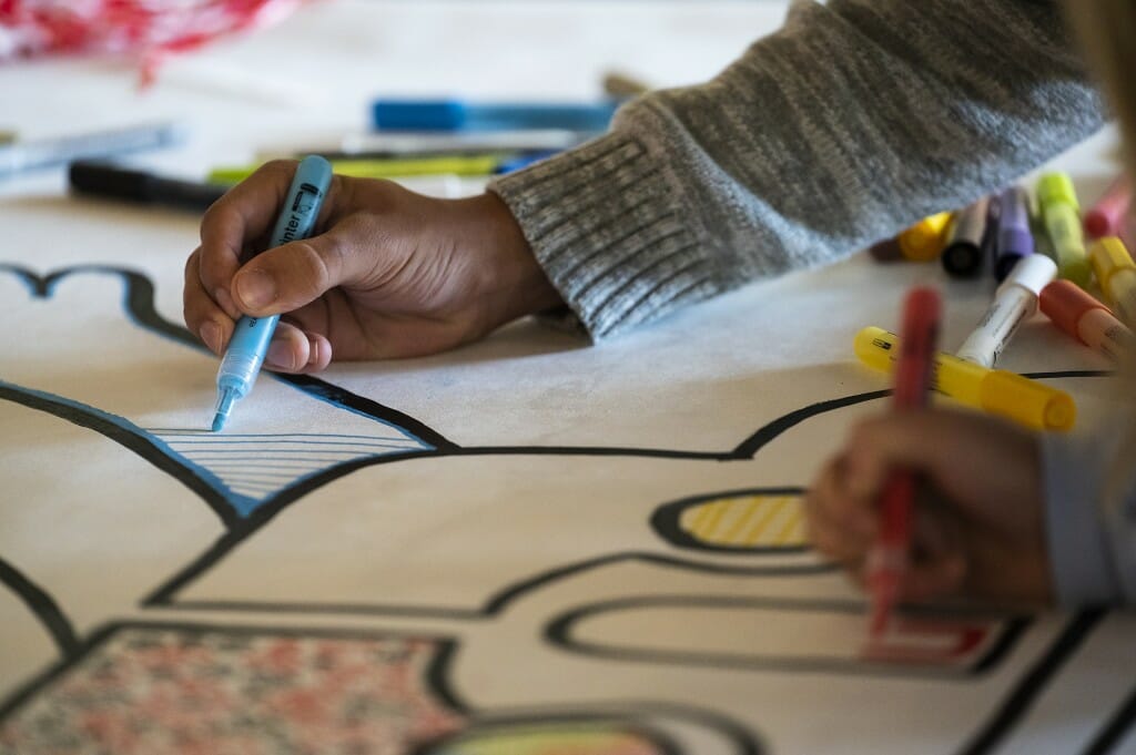 Two students write with markers on a large piece of paper.