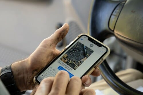 Two hands hold an iPhone showing a text message chain.