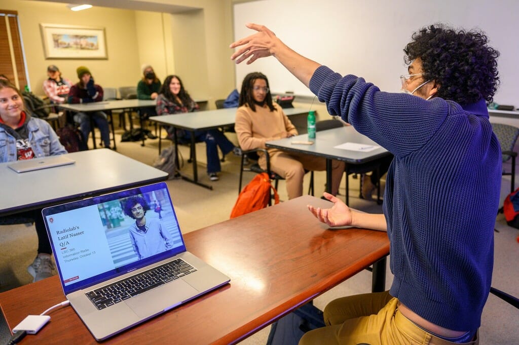 Nasser gestures while answering student questions about how to share science when scientific questions have changing answers. Nasser was visiting Information Radio (LSC360), in Hiram Smith Hall. Nasser’s said: “Lead with the question, then be like, ‘There are all these people going to these absurd lengths to try to answer this question. This is the best they’ve come up with. Maybe this is true. This is as far as we can tell what’s true. And maybe it’s going to change tomorrow. Being honest with you, it’s probably going to change tomorrow. But this is the best we’ve got.’ To me, that’s a much more honest and faithful to science way to do it. And it feels for people reading it like they’re not being jerked around.”