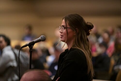 A woman from the audience speaks into a microphone.