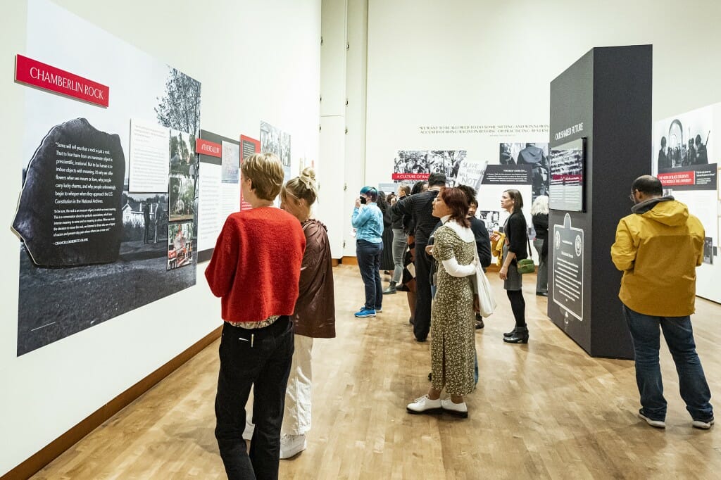 A group of people engage with exhibit installations for Sifting & Reckoning.