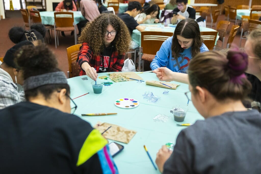 A table full of people paint suncatchers and chat.