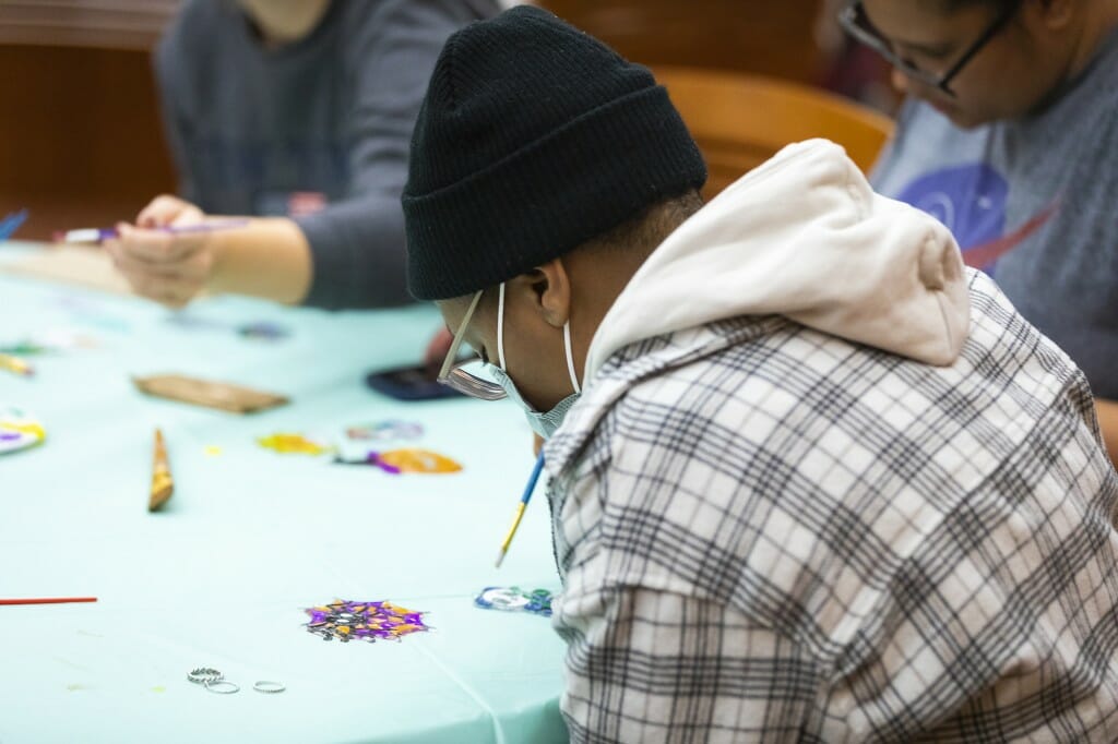 A person hunches over a table to focus on what they're painting.