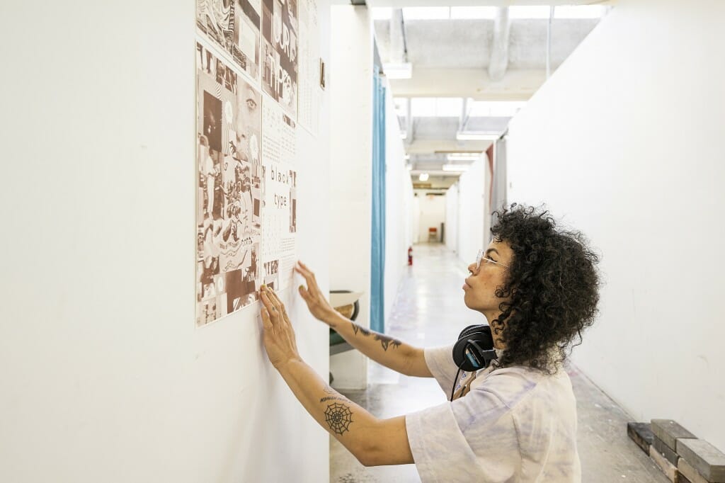 A person hangs a print on the wall.