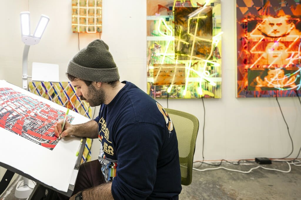 A man works on art at a desk.