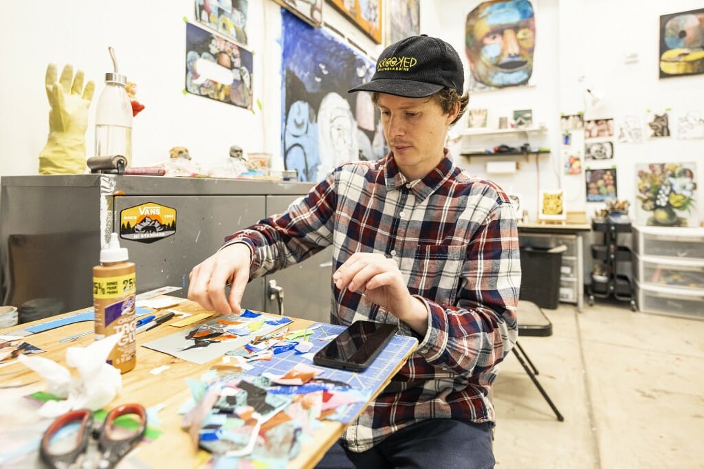 A man works on a colorful collage.