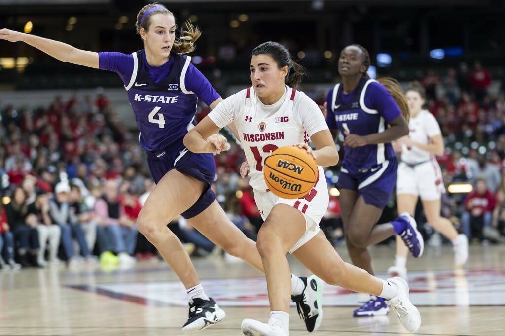 A woman in a white uniform dribble past a woman in the blue uniform.