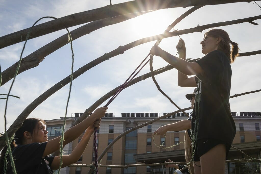 Students Paige Blackdeer and Abbey Woldt help construct the ciiporoke. Woldt, a freshman from Cross Plains, Wisconsin, honed the ends of lodge poles and tied them together, and she scaled the structure to help secure the canvas. “When I heard about this opportunity, I thought, Wow, I have to be involved,” said Woldt, a pre-nursing student who is Ho-Chunk. “I really hope this serves to help students and others learn more about the Native people who originally were on this land and to see our culture in real life and in person.”