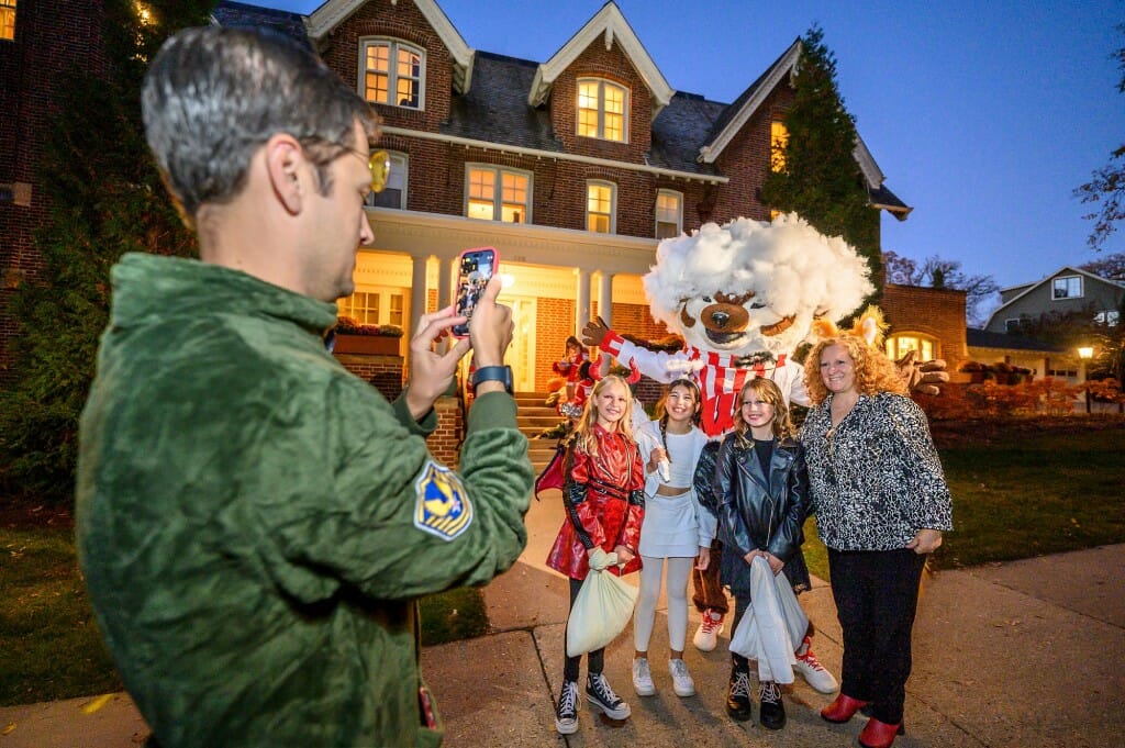 Chancellor Jennifer Mnookin and Bucky Badger pose for a photo with trick-or-treaters outside Olin House.