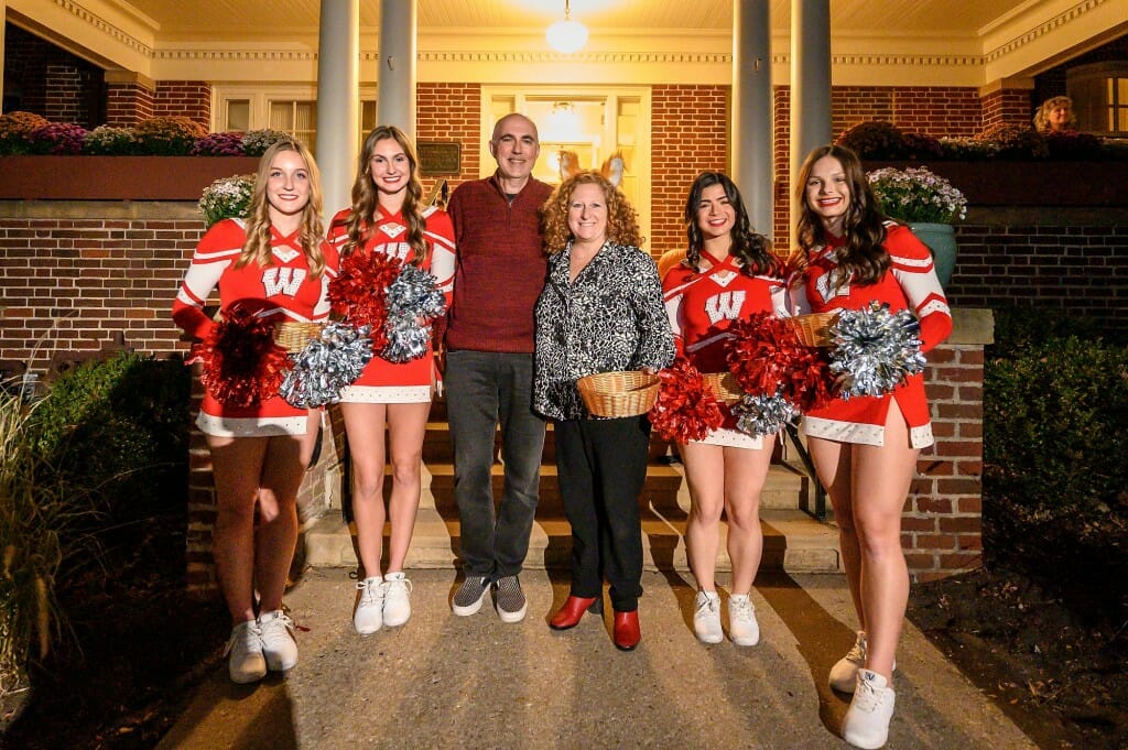 Chancellor Jennifer Mnookin and her husband, political science professor Joshua Foa Dienstag, pose with members of the UW Spirit Squad for a photo on the steps of Olin House.