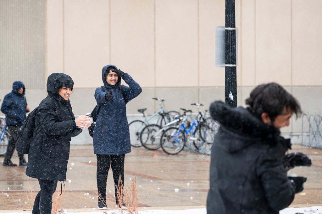 Two women throw snowballs at a man.