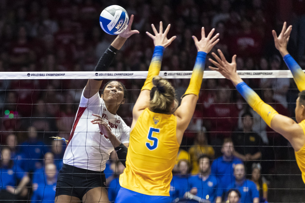 Devyn Robinson (#10) spikes the ball as Pitt players try to block it.