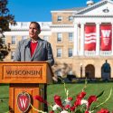 Aaron Bird Bear speaks from a podium bearing the UW–Madison crest on Bascom Hill.