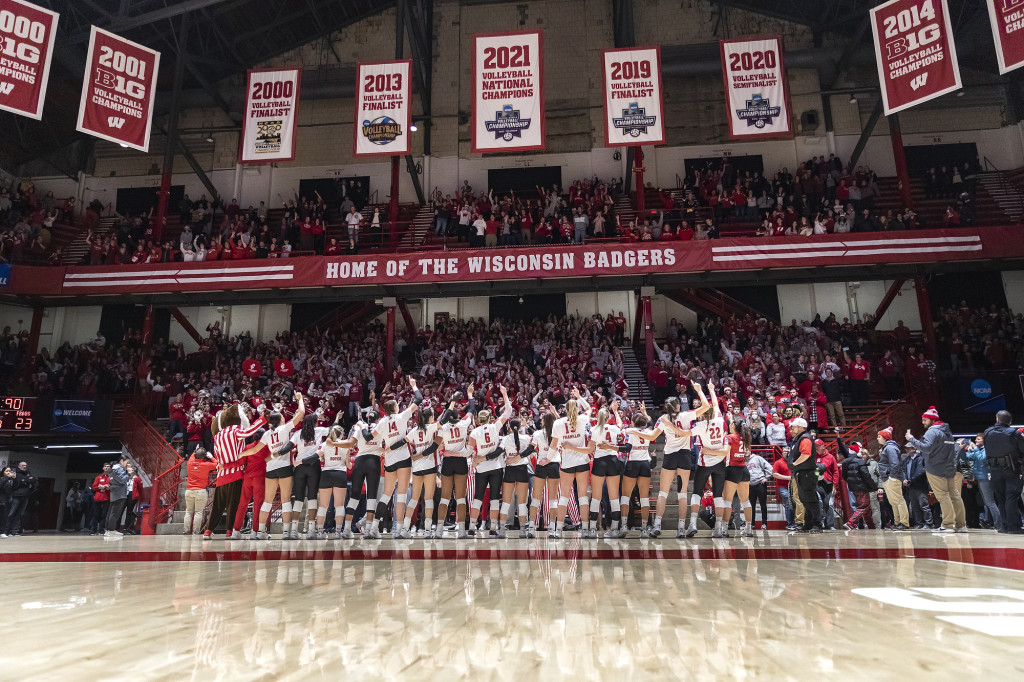 The team lines up on the court, arms around each other, singing.