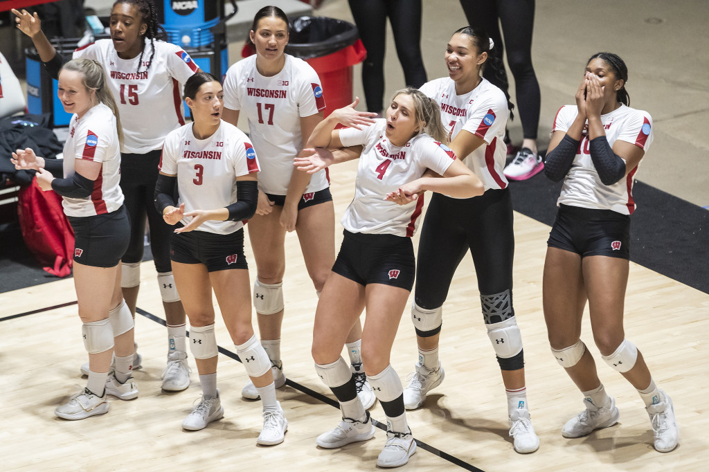 Volleyball players dance and mime on the sideline.