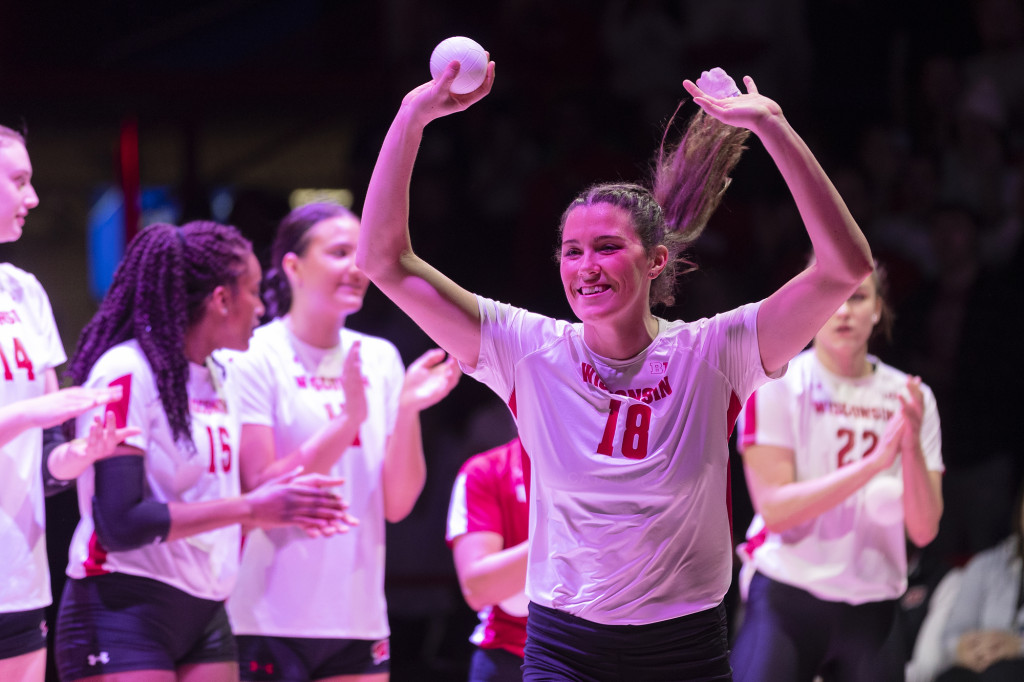 A player smiles and holds up her arms triumphantly as she jogs onto the court.