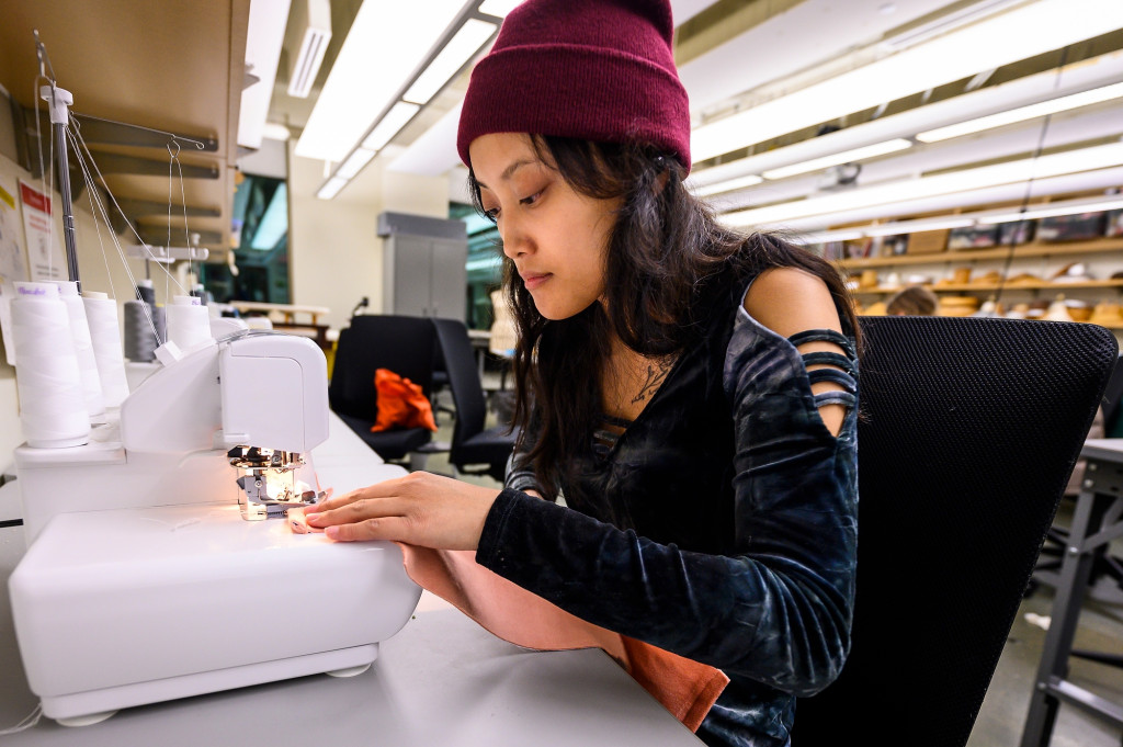 A woman sits at a sewing machine and sews.