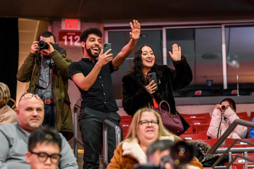 Proud friends and family members cheer and wave.