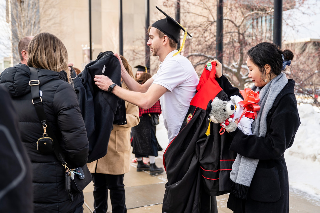 A man takes off his coat outdoors.