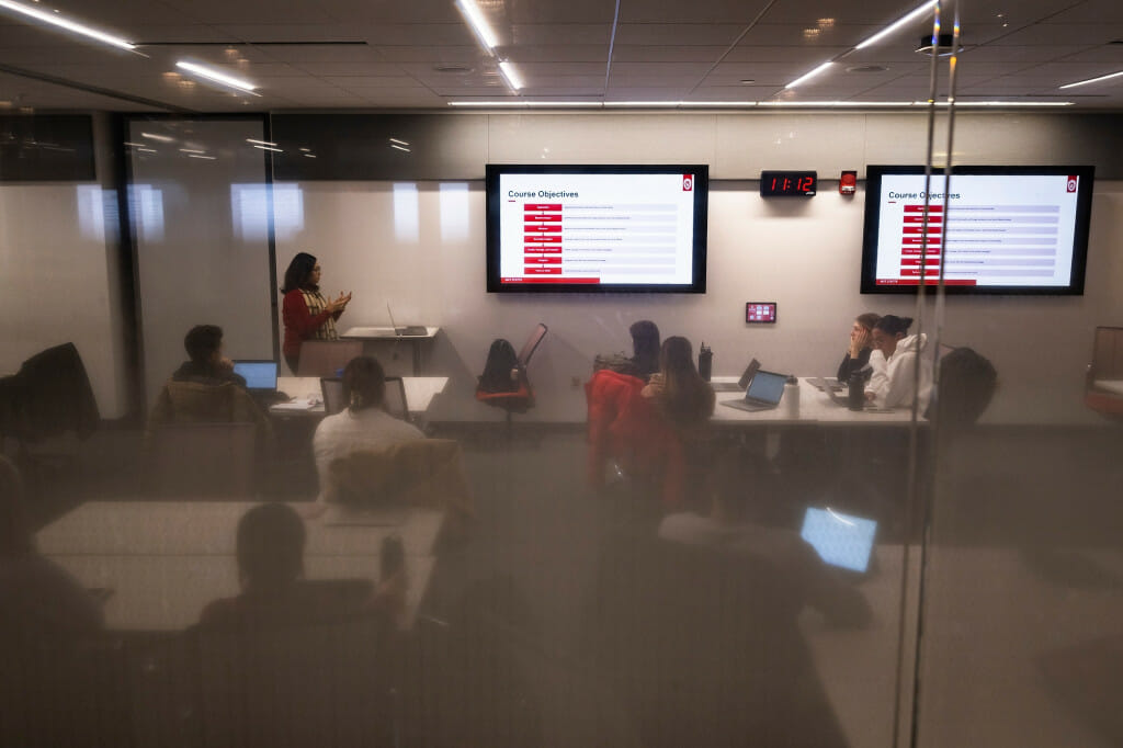 A classroom is seen through a window.