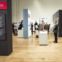 A wide view of the Sifting and Reckoning exhibition with visitors stopping to read materials on display.