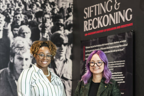 A portrait of Taylor Bailey and Kacie Lucchini Butcher standing in the Sifting and Reckoning exhibition.