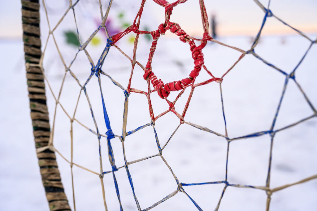 A hoop (dakobijigan-minawaa) awaits a spear-thrower. The red center represents ayaabe (the buck) and is worth 3 points, the blue ring represents niiniijaanii (the doe) and is worth 2 points, and the unpainted outer ring represents gidigaakoohns (the fawn) and is worth 1 point. 