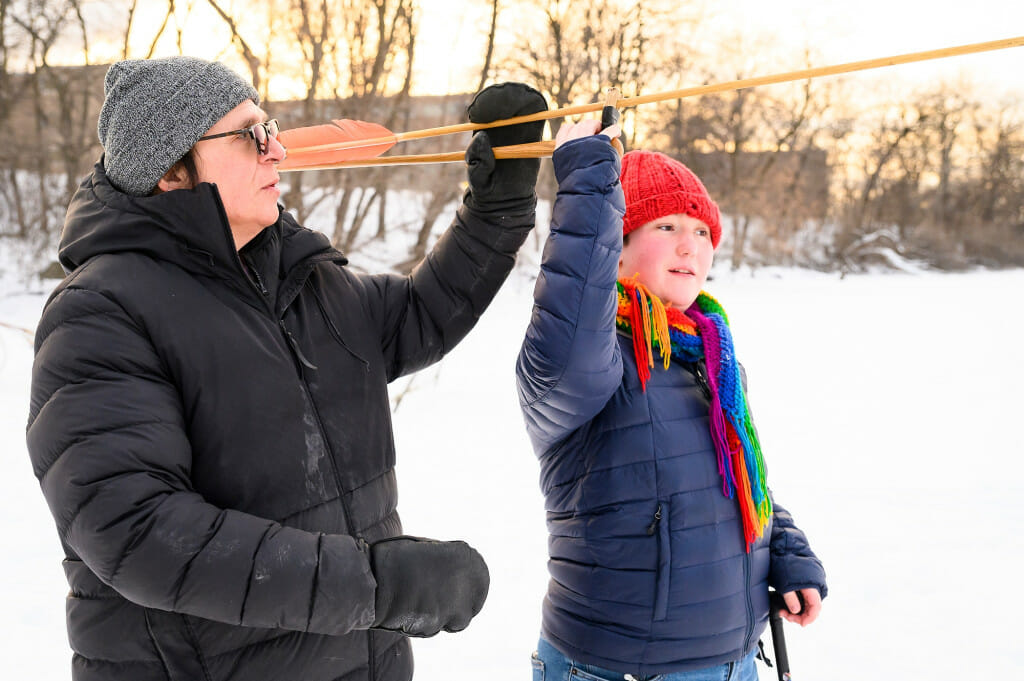 Program organizer Wayne Valliere (Lac du Flambeau Ojibwe), left, helps undergraduate and Ojibwe language student Emmett Lockwood position an atlatl (spear throwing tool) and spear.