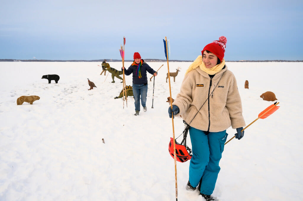 Undergraduates and second semester Ojibwe language students Emmett Lockwood, left, and Rowan Hildebrandt collect spears lying amid dinosaur, bear and deer targets.