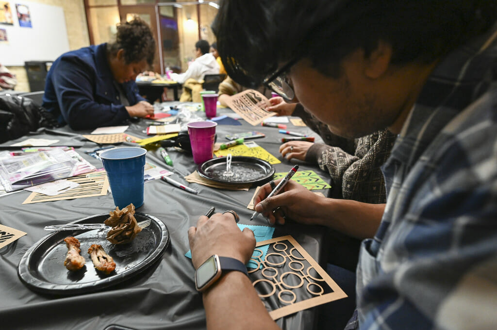 Seated at a table covered in crafting supplies, Nilay Bhadra leans in to decorate a quilting square.