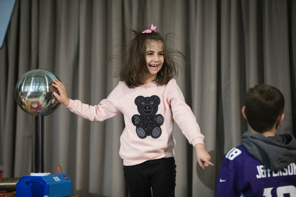 Amal Al-Subu’s hair raises from the electric charge from touching a Van de Graaff generator.