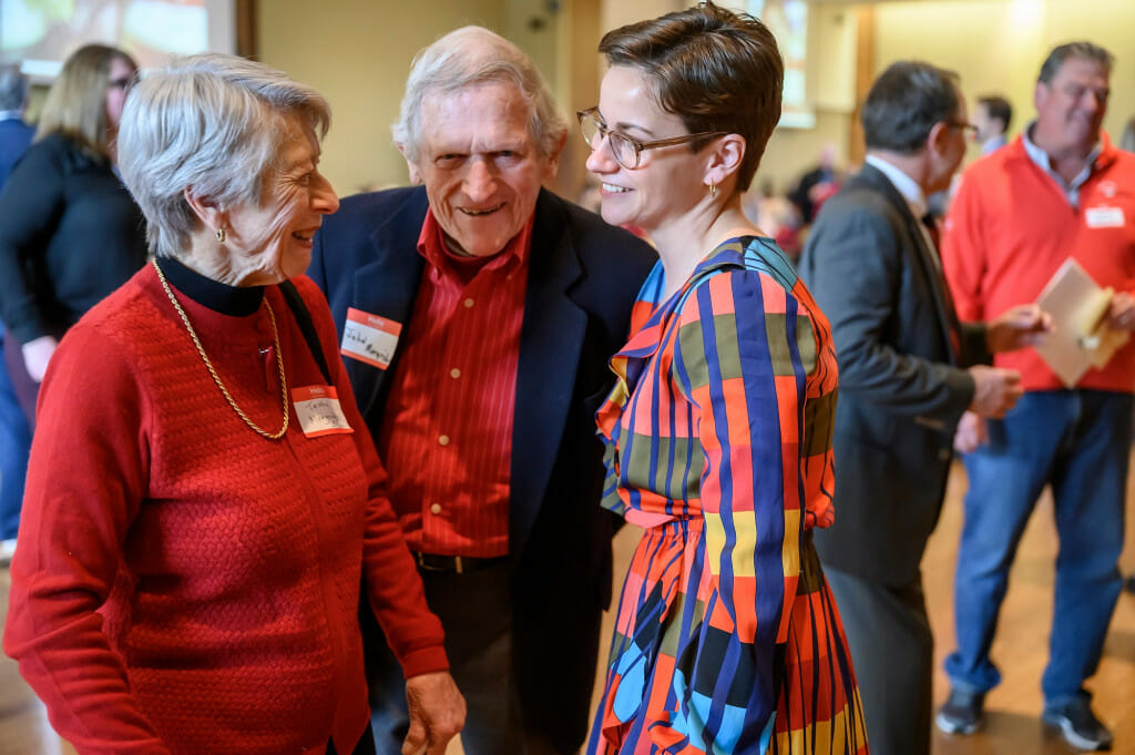 A couple speaks to a woman.