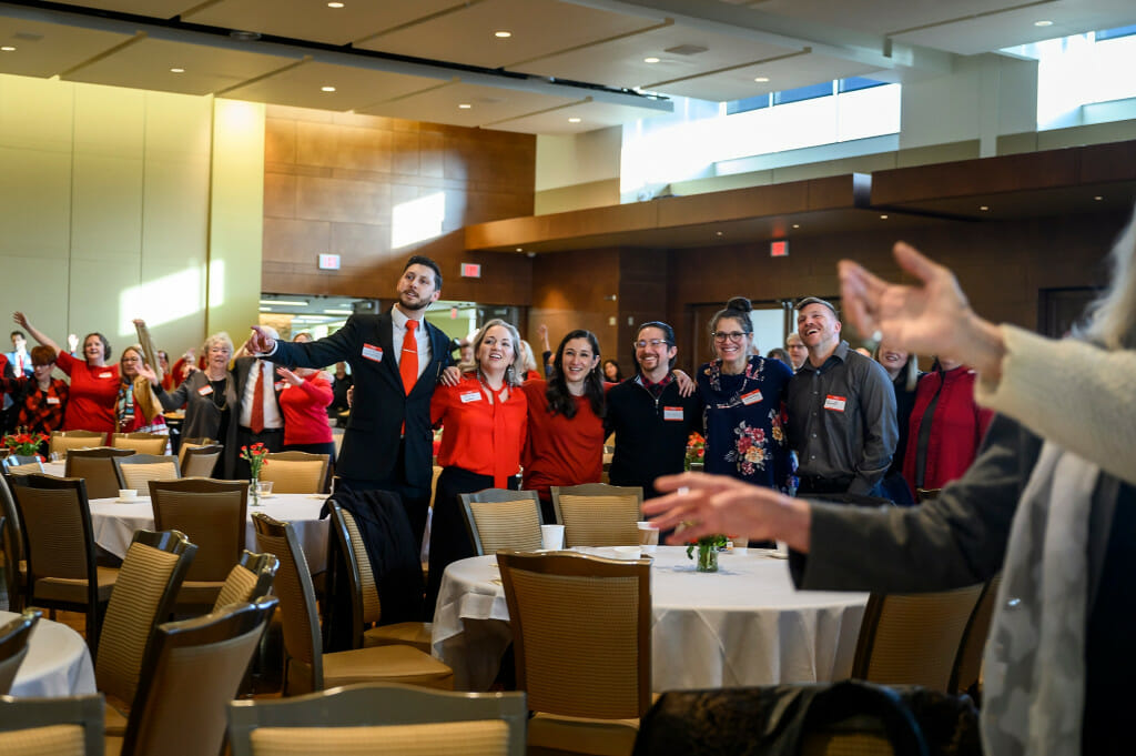 People sing while standing arm-in-arm.