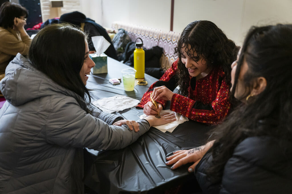 Maha Mustafa paints a henna decoration on the hand of Arabelle Liberacki.