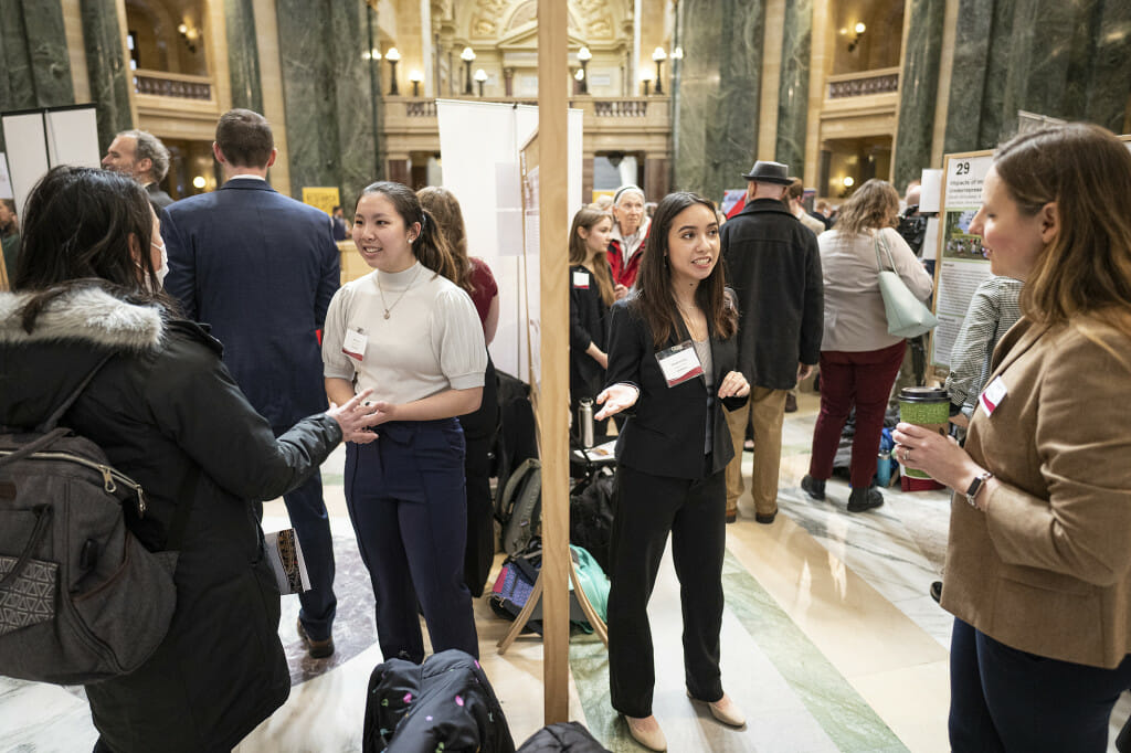 UW–Madison students Sherrie Wu (center left) and Samantha Greco (center right) talk about their research projects.