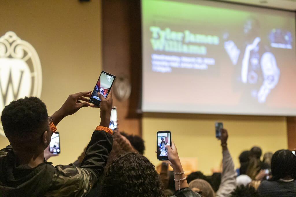 Audience members take photos and videos of Williams.