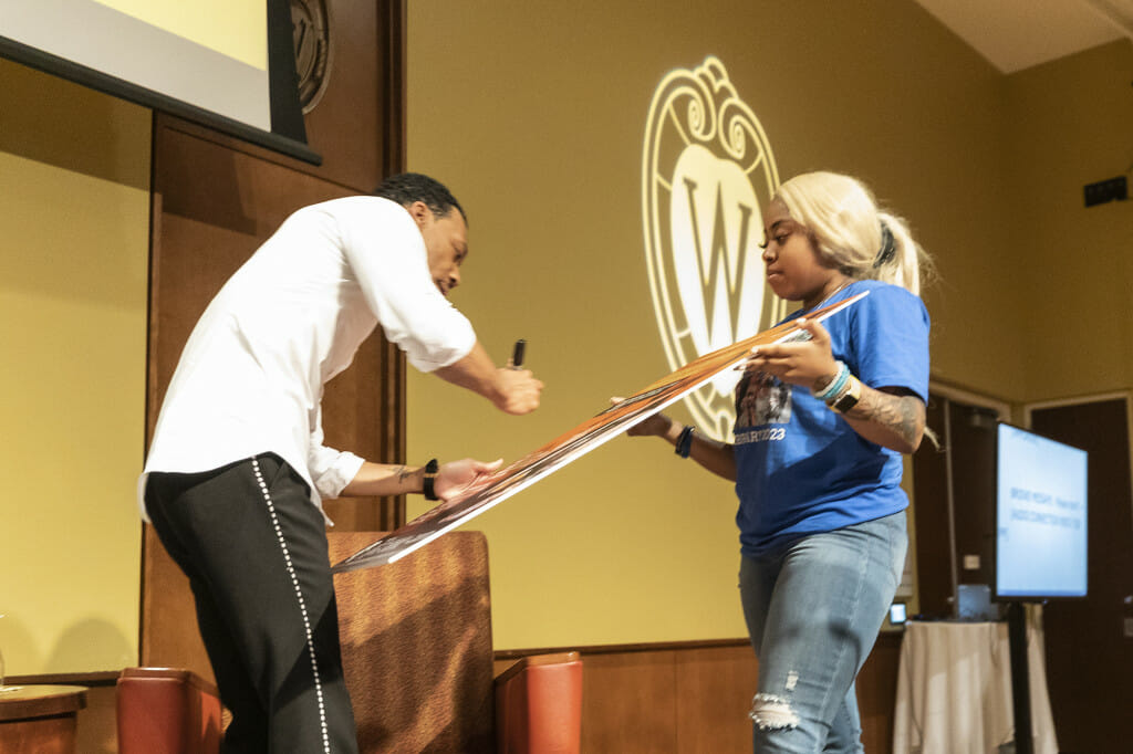 Williams (left) signs the event poster with the help of Daijahnique Lloyd, member of the Black History Month Planning Committee.