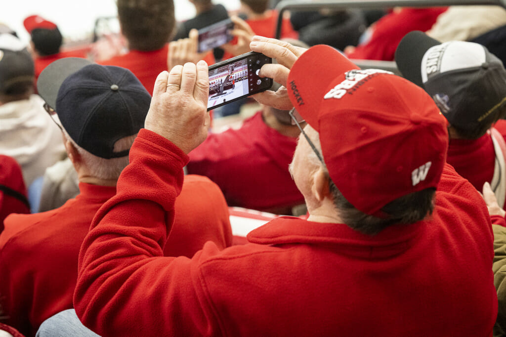 Fans cheer and take photos of the team on their phones.