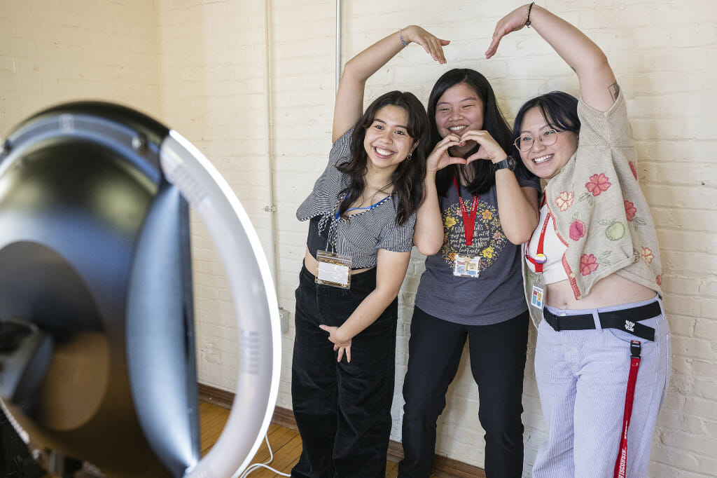 Three women strike silly poses for a camera.