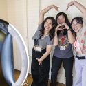 Three women strike silly poses for a camera.