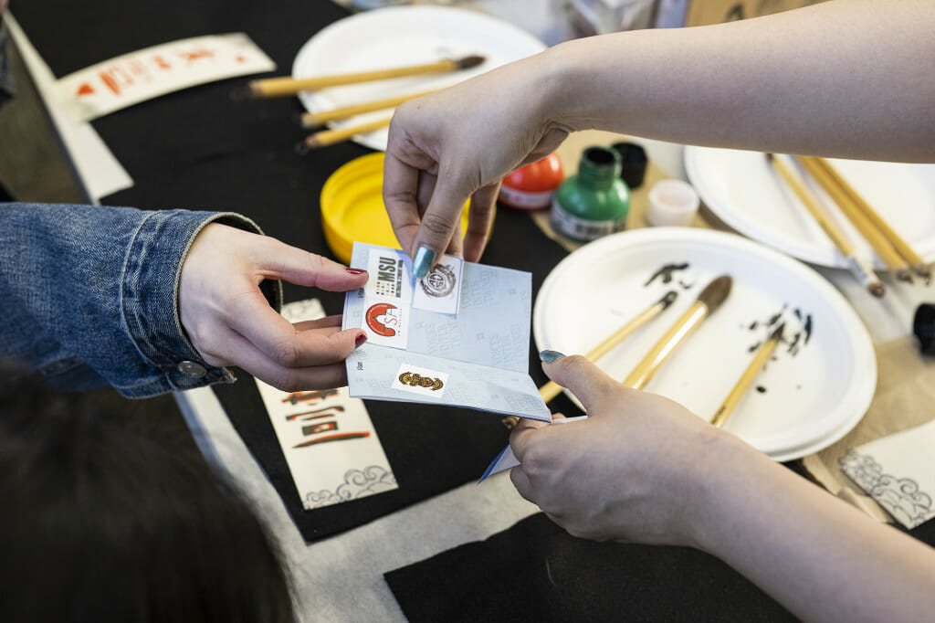 A hand puts a stamp into a small booklet.