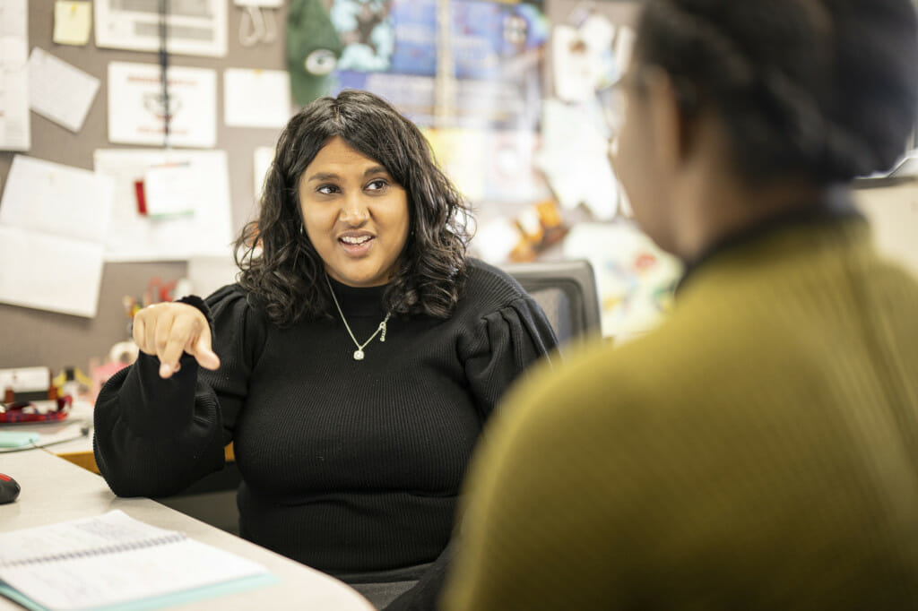 A woman smiles as she speaks with a student.