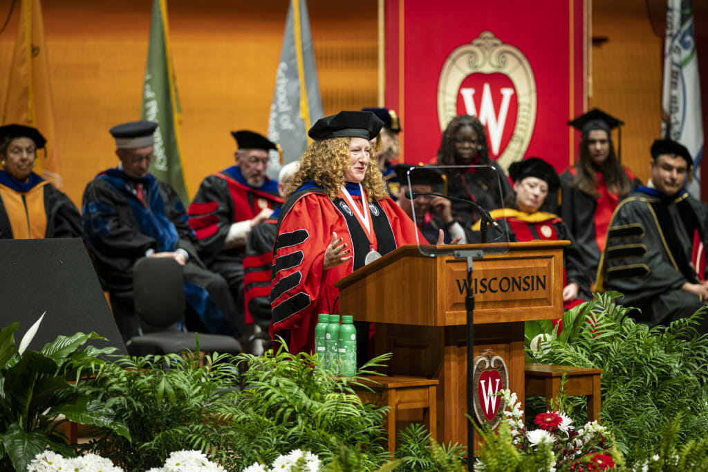 A woman gestures while talking at a podium.