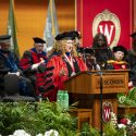 A woman gestures while talking at a podium.