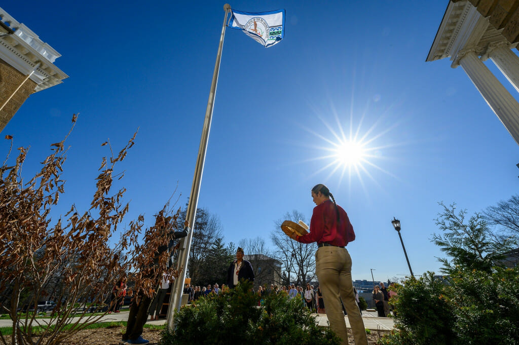 From right to left, Cordell Funmaker, Ho-Chunk Nation tribal member; Marcus WhiteEagle, Ho-Chunk marine veteran; and Marlon WhiteEagle, president of the Ho-Chunk Nation and marine veteran; play the hand drum and raise the Ho-Chunk Nation’s flag in front of Bascom Hall at the University of Wisconsin–Madison on April 12, 2023.