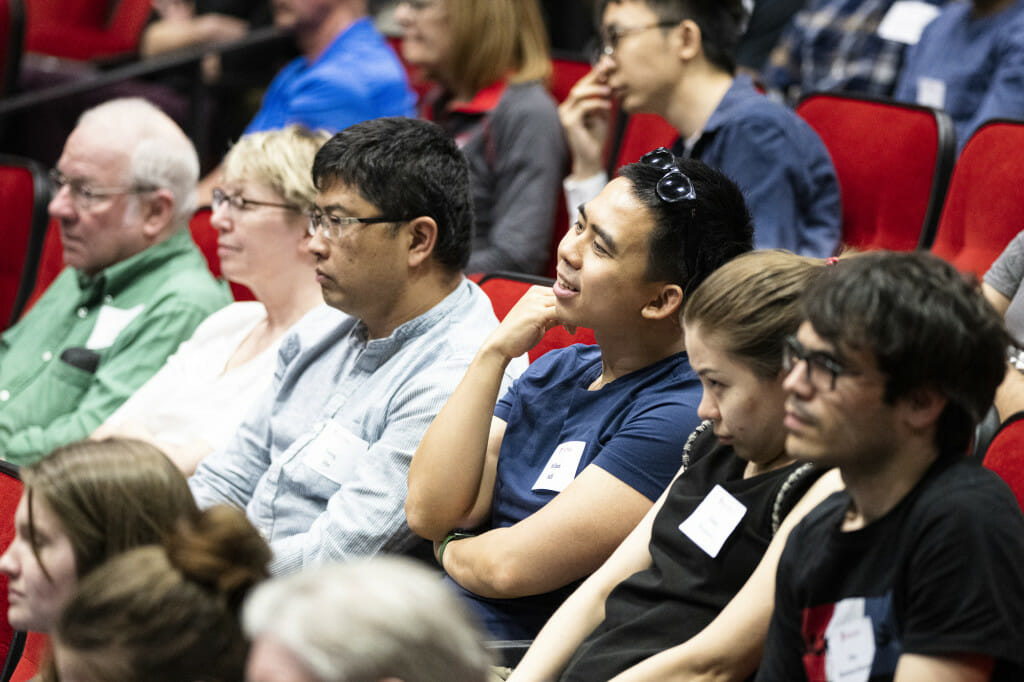 People sitting in an auditorium have thoughtful looks as they listen.