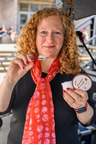 Chancellor Mnookin holds a cup of ice cream in one hand and a spoon in the other.