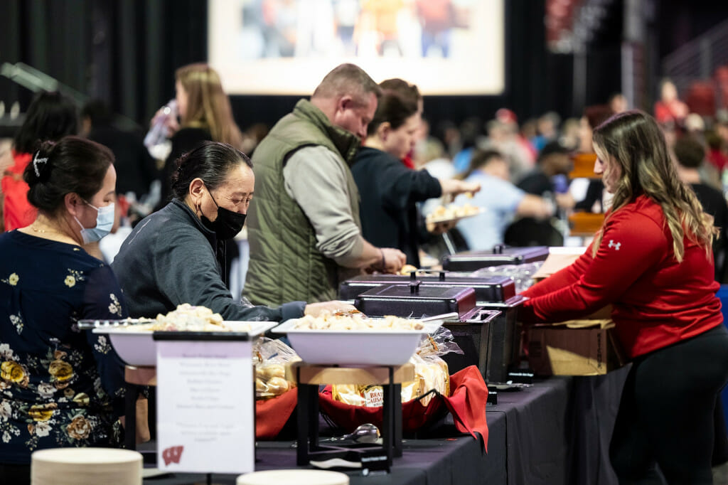 People move down a buffet line serving themselves food.