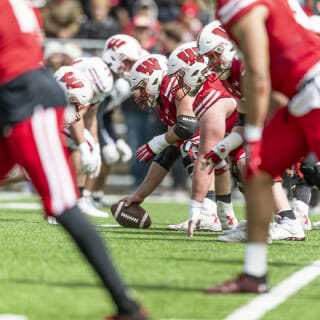 Players in red and players in white line up on opposite sides of the line of scrimmage.