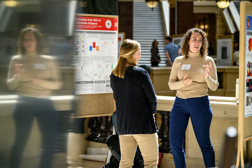 Standing in the Capitol rotunda, two women discuss a research poster on display.